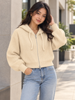 Woman wearing beige cropped ribbed zip hoodie by Purple Imli in a city street look