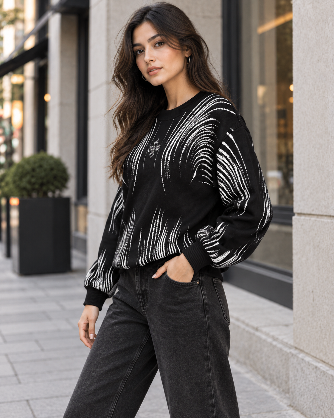 Woman wearing black brushstroke rhinestone sweater by Purple Imli in a city street look