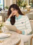 Woman wearing green striped bow zip-up sweater by Purple Imli in a city street look