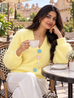 Woman wearing light yellow fuzzy daisy button cardigan by Purple Imli in a city street look