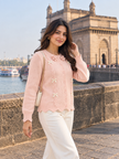 Woman wearing pink scalloped bow cardigan by Purple Imli in a city street look