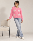 Woman wearing pink fuzzy pearl flower cardigan by Purple Imli in a city street look