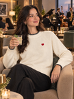 Woman wearing cream little heart crew-neck sweater by Purple Imli in a city street look